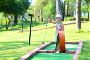 Little toddler girl playing mini golf