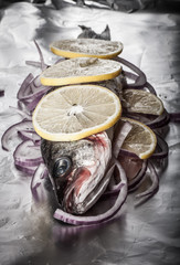 Fish prepared for roasting on the foil with lemon and onion.tint