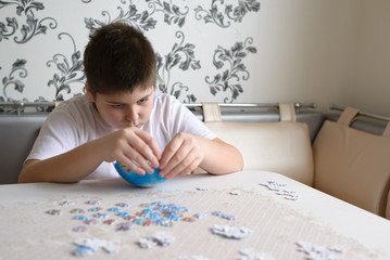 Obraz na płótnie Canvas Teenager boy collects puzzles from Globe