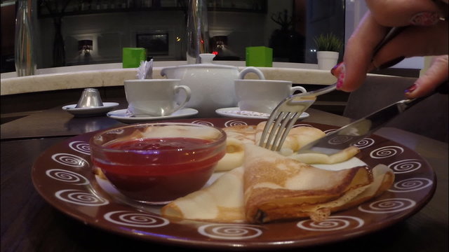 Girl eats pancakes with raspberry jam in a cafe restaurant 