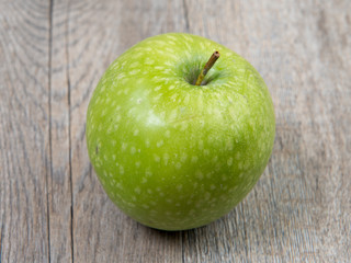 green apple placed on a wooden table