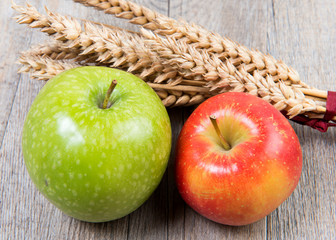 apples and wheat cobs placed on a wooden table