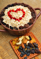 Oatmeal in ceramic plate, spoon, raisins, cashews and almonds.