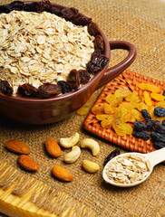 Oatmeal in ceramic plate, spoon, raisins, cashews and almonds.