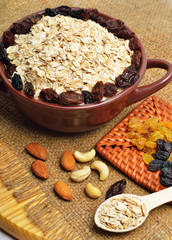 Oatmeal in ceramic plate, spoon, raisins, cashews and almonds.