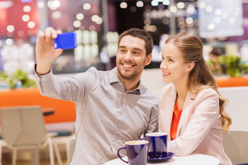 happy couple with smartphone taking selfie in mall