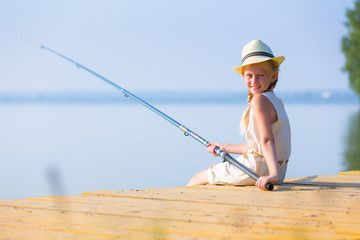 Girl in a dress and a hat with a fishing rod