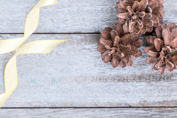 Pine cones and golden ribbon on wood background