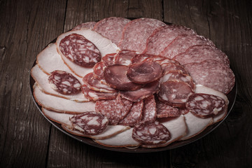 Obraz premium plate with different sliced sausage on an old wooden table