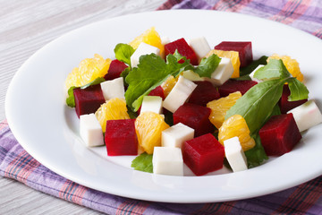 Fresh beet salad with oranges, cheese and arugula on a table