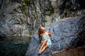 Naklejka premium beautiful girl posing in dress at the waterfall