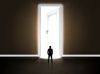 Obraz premium Business man looking at big bright opened door