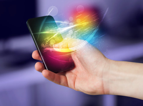 Hand holding smart phone with abstract glowing lines