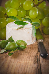 Smelly blue cheese on a wooden rustic table with grape