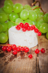 Smelly blue cheese on a wooden rustic table with red currants
