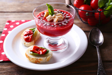 Gazpacho soup in glass bowl, on color wooden background