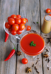 Tomato juice in goblet and fresh vegetables on wooden