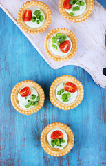 Tartlets with greens and vegetables with sauce on table