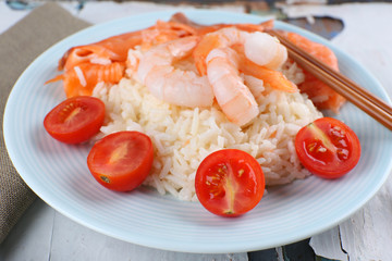 Boiled rice and shrimps, salmon on plate, on wooden background