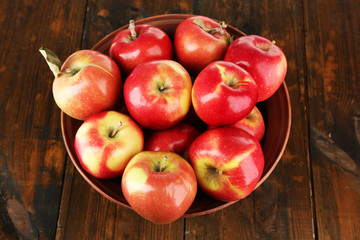 Bowl of red apples on wooden table background