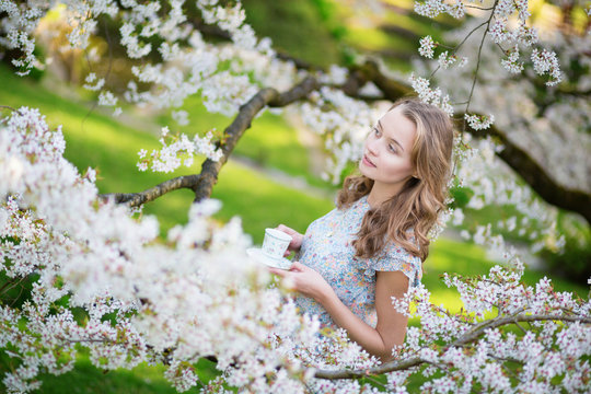 Girl drinking tea in cherry blossom garden