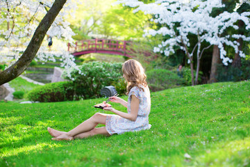 Naklejka na ściany i meble Girl eating sushi in cherry blossom garden