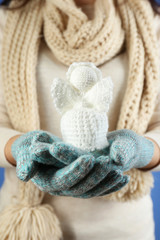 Knitted Christmas angel in female hand on color background