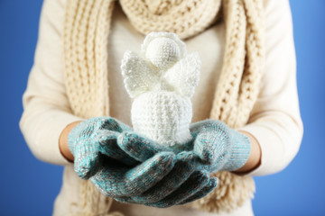Fototapeta na wymiar Knitted Christmas angel in female hand on color background