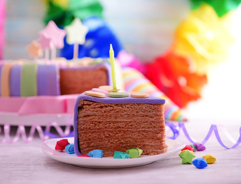 Delicious piece of birthday cake on table on bright background