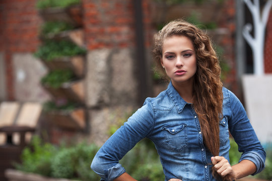Beautiful young girl with curly hair outdoors in denim shirt