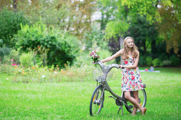 Happy young girl with bicycle and flowers