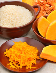 ripe raw pumpkin with grated pumpkin and uncooked rice on the br