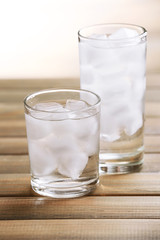 Glasses with ice cubes on wooden table