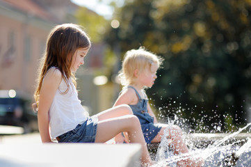 Little sisters having fun in a fountain