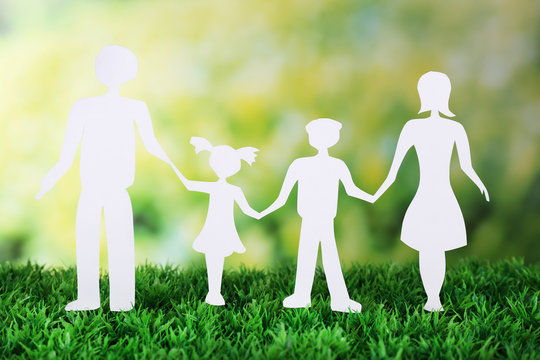 Paper family on green grass on light background