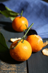 Juicy ripe tangerines with leaves on wooden table