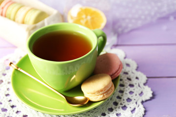 Colorful macaroons with cup of tea on wooden background