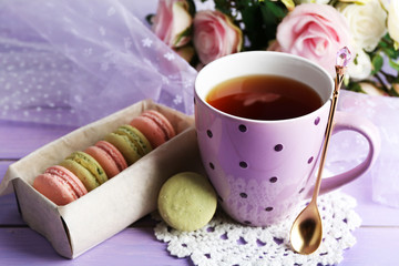 Colorful macaroons with cup of tea on wooden background