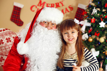 Fototapeta na wymiar Santa Claus with little cute girl near fireplace and Christmas