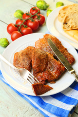Roasted meat and vegetables on plate, on wooden table
