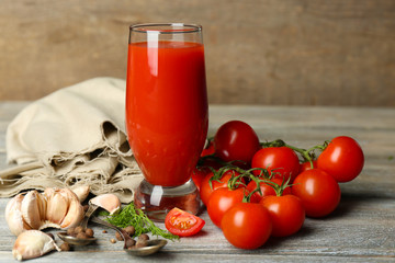 Glass of tasty tomato juice and fresh tomatoes on wooden table