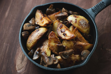 Roasted potatoes with peel and mushrooms in a frying pan
