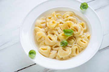 Close-up of cheese tortellini in bouillon, horizontal shot