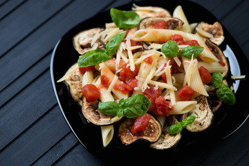 Black glass plate with italian pasta alla Norma, studio shot