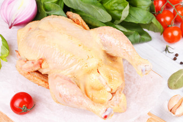 Fresh raw chicken prepared for roast with thyme and tomatoes
