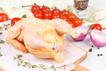 Fresh raw chicken prepared for roast with thyme and tomatoes