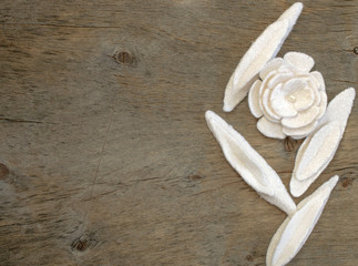 The wooden background and white floral pieces of white felt