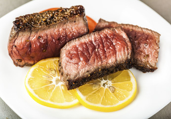 Sliced grilled meat with slices of lemon
