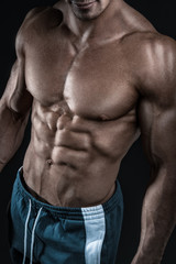 Fototapeta na wymiar Strong athletic man fitness model showing torso muscles
