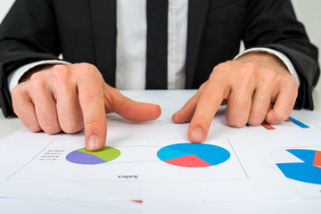 Hands of a businessman analysing two pie graphs